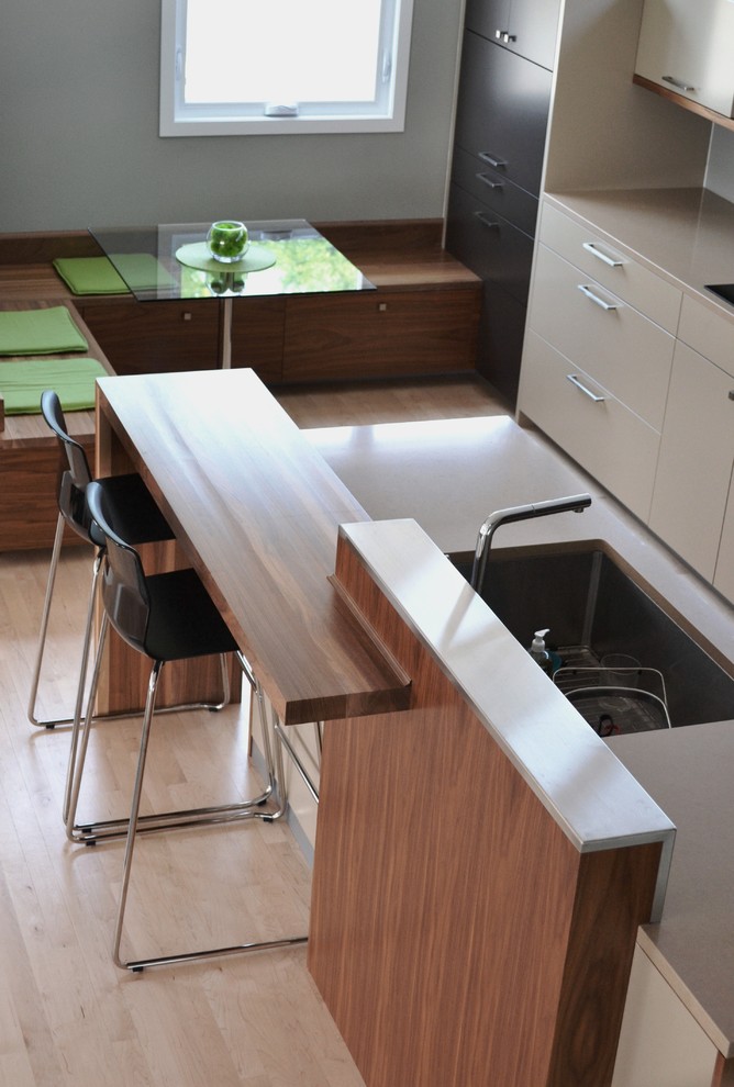 Immagine di una cucina contemporanea di medie dimensioni con lavello sottopiano, ante lisce, ante beige, top in quarzite, elettrodomestici da incasso e parquet chiaro
