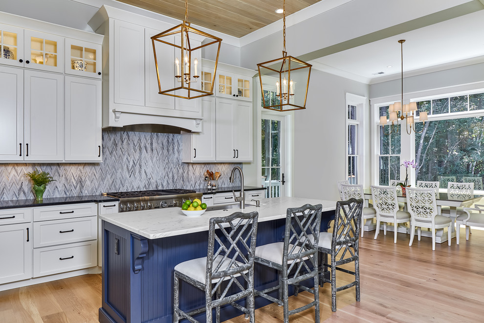 Inspiration for a large coastal galley light wood floor and brown floor kitchen remodel in Charleston with a drop-in sink, white cabinets, blue backsplash, mosaic tile backsplash, stainless steel appliances and an island