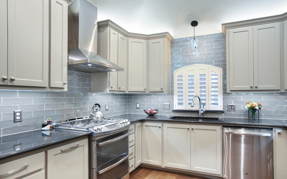 Modern inredning av ett avskilt, litet u-kök, med en undermonterad diskho, luckor med infälld panel, beige skåp, granitbänkskiva, blått stänkskydd, stänkskydd i glaskakel, rostfria vitvaror och mellanmörkt trägolv