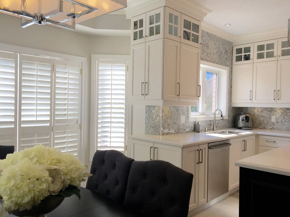 Medium sized classic u-shaped enclosed kitchen in Toronto with a double-bowl sink, recessed-panel cabinets, white cabinets, engineered stone countertops, grey splashback, mosaic tiled splashback, stainless steel appliances, porcelain flooring and an island.