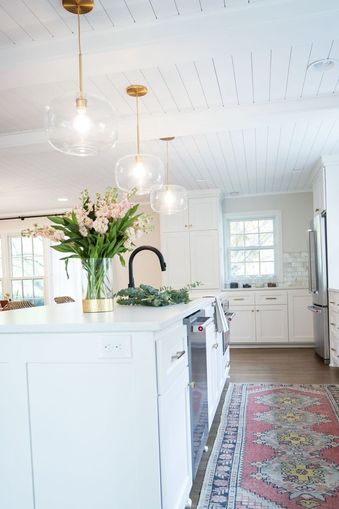 Exempel på ett stort klassiskt vit vitt kök, med en undermonterad diskho, skåp i shakerstil, vita skåp, bänkskiva i kvarts, vitt stänkskydd, stänkskydd i marmor, rostfria vitvaror, mellanmörkt trägolv, en köksö och brunt golv