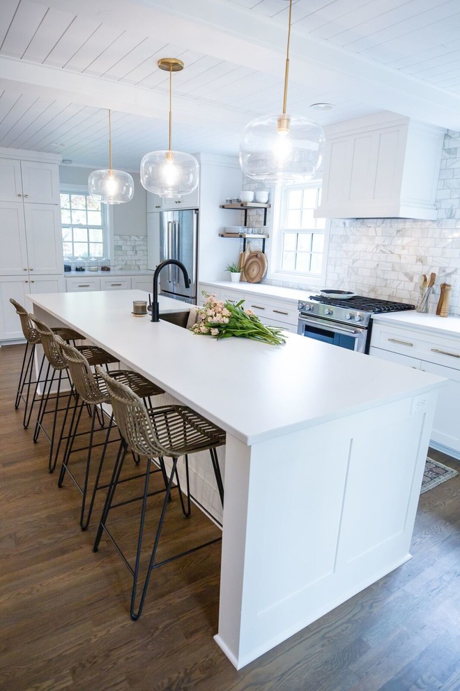 Idéer för att renovera ett stort vintage vit vitt kök, med en undermonterad diskho, skåp i shakerstil, vita skåp, bänkskiva i kvarts, vitt stänkskydd, stänkskydd i marmor, rostfria vitvaror, mellanmörkt trägolv, en köksö och brunt golv