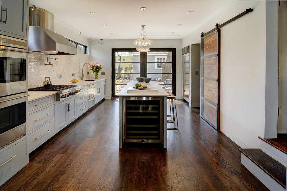 Example of a mid-sized transitional medium tone wood floor eat-in kitchen design in New York with a single-bowl sink, blue cabinets, quartzite countertops, beige backsplash, stone tile backsplash, stainless steel appliances, an island and shaker cabinets