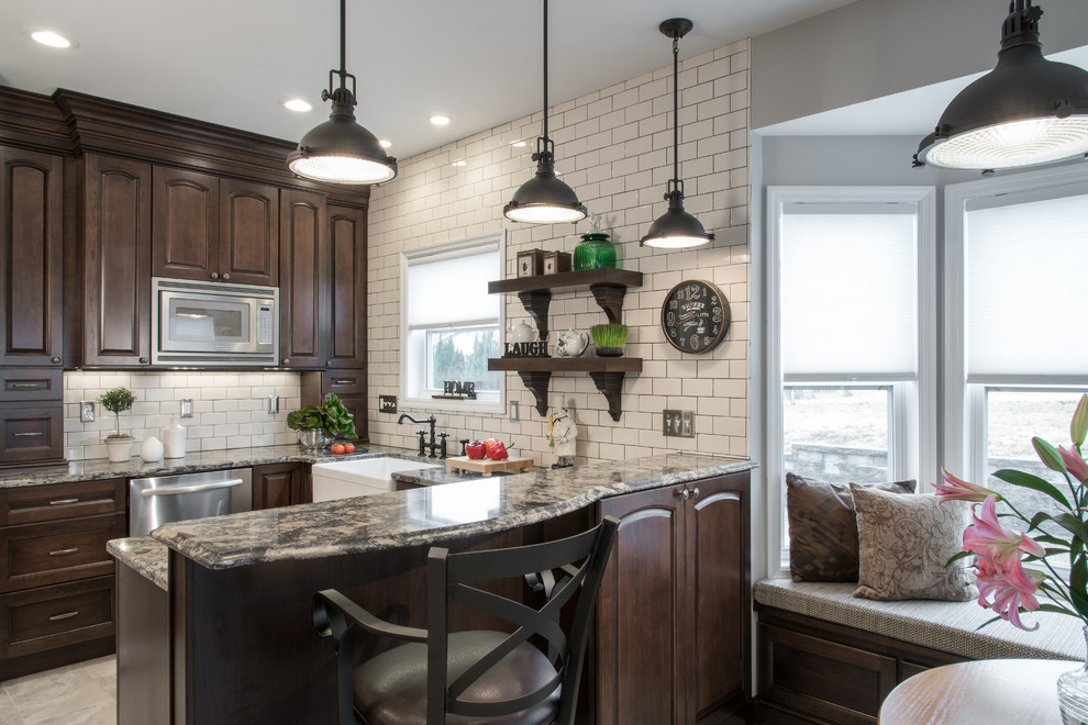 Mid-sized transitional u-shaped porcelain tile eat-in kitchen photo in St Louis with a farmhouse sink, raised-panel cabinets, dark wood cabinets, quartz countertops, white backsplash, subway tile backsplash, stainless steel appliances and a peninsula