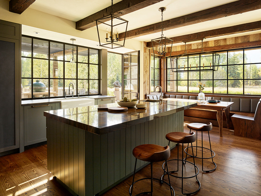 Aménagement d'une cuisine américaine montagne avec un évier de ferme, fenêtre, un sol en bois brun et îlot.