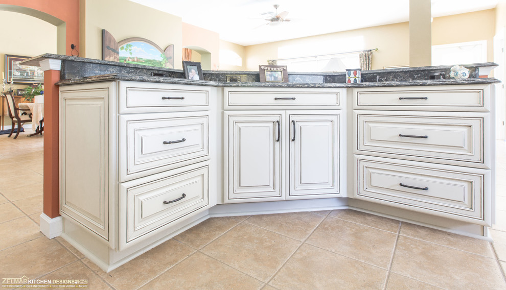 Eat-in kitchen - mid-sized traditional l-shaped eat-in kitchen idea in Orlando with an undermount sink, recessed-panel cabinets, beige cabinets, quartz countertops, multicolored backsplash, travertine backsplash, stainless steel appliances and an island