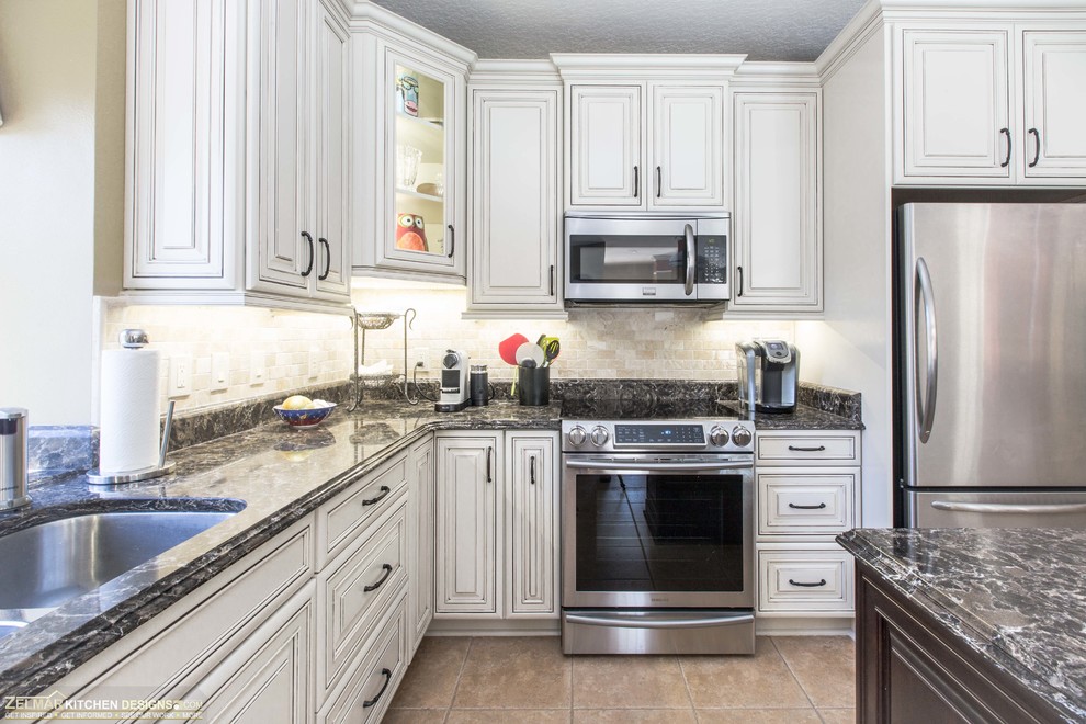 Inspiration for a mid-sized timeless l-shaped eat-in kitchen remodel in Orlando with an undermount sink, recessed-panel cabinets, beige cabinets, quartz countertops, multicolored backsplash, travertine backsplash, stainless steel appliances and an island