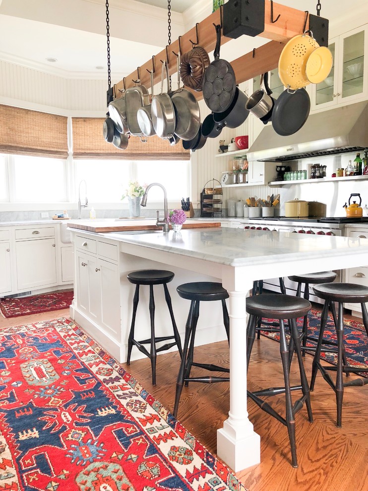 Stilmix Küche mit Landhausspüle, Schrankfronten im Shaker-Stil, weißen Schränken, Küchengeräten aus Edelstahl, braunem Holzboden, Kücheninsel, braunem Boden und grauer Arbeitsplatte in Bridgeport