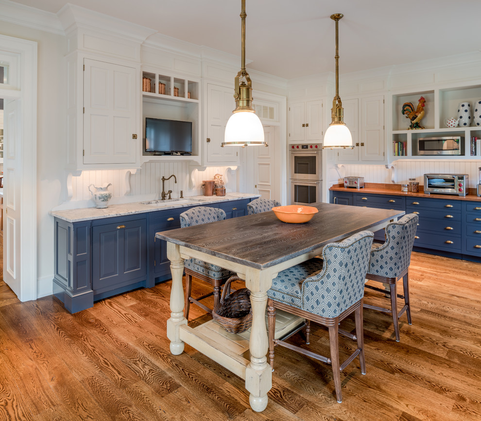 Exempel på ett stort klassiskt brun brunt l-kök, med en undermonterad diskho, luckor med upphöjd panel, blå skåp, träbänkskiva, vitt stänkskydd, stänkskydd i trä, mellanmörkt trägolv, en köksö och brunt golv