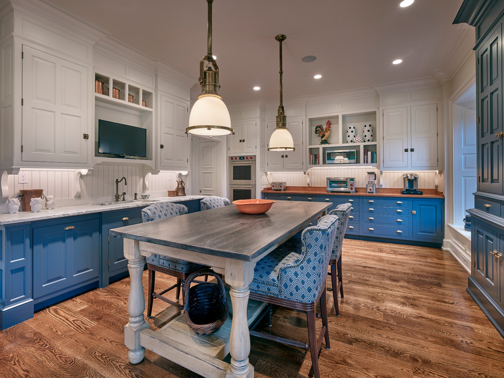 Idéer för avskilda, stora vintage vitt u-kök, med en undermonterad diskho, luckor med upphöjd panel, blå skåp, marmorbänkskiva, vitt stänkskydd, integrerade vitvaror, mellanmörkt trägolv, en köksö, stänkskydd i trä och brunt golv