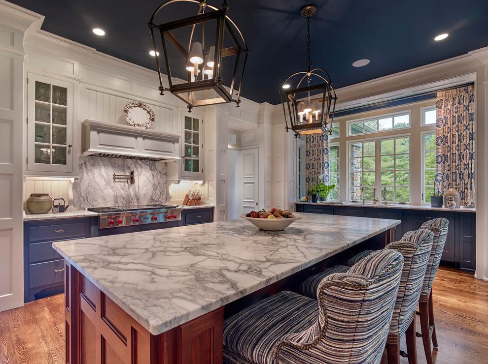 Enclosed kitchen - large traditional u-shaped medium tone wood floor and brown floor enclosed kitchen idea in Philadelphia with an undermount sink, blue cabinets, marble countertops, an island, raised-panel cabinets, white backsplash, wood backsplash, paneled appliances and white countertops