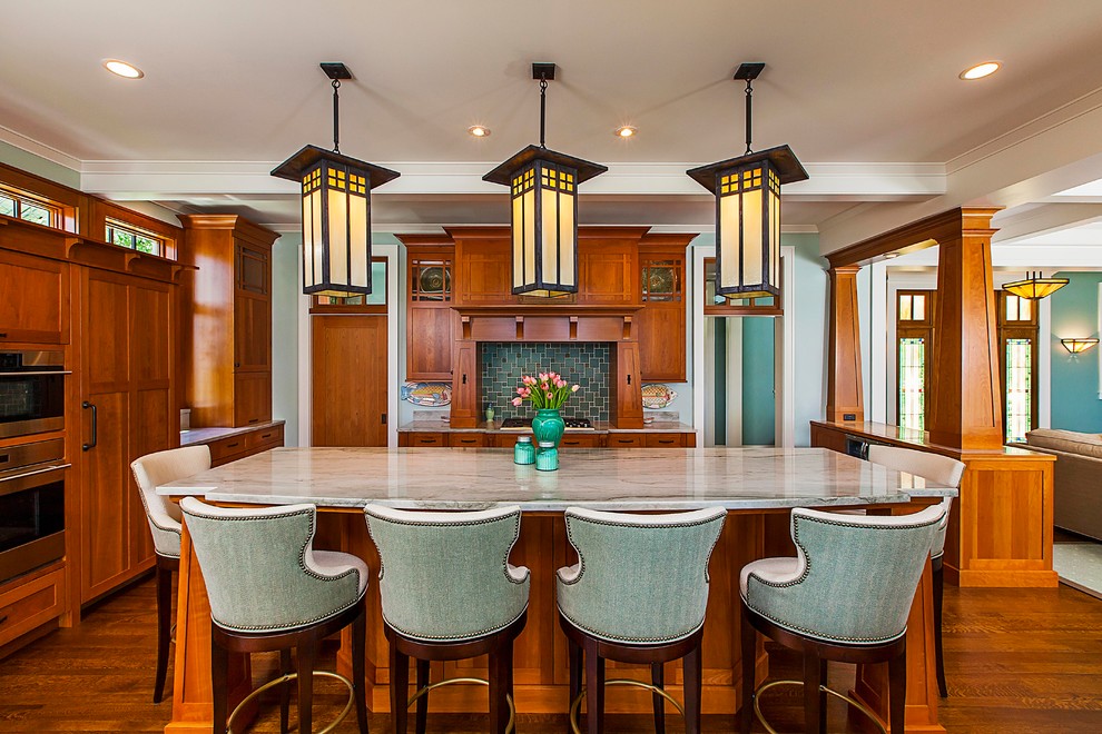 This is an example of a large traditional open plan kitchen in Grand Rapids with medium wood cabinets, engineered stone countertops, stainless steel appliances, an island, shaker cabinets, green splashback and medium hardwood flooring.