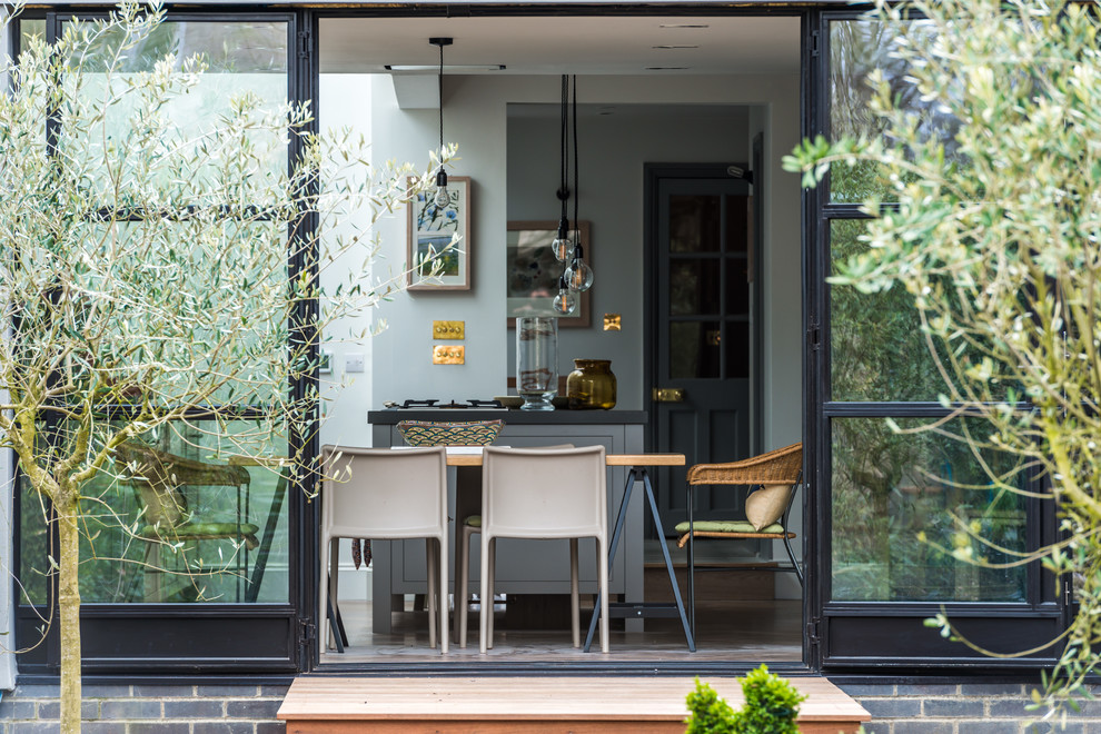 Eat-in kitchen - large contemporary u-shaped light wood floor eat-in kitchen idea in London with an undermount sink, flat-panel cabinets, gray cabinets, solid surface countertops, white backsplash, marble backsplash, stainless steel appliances and an island