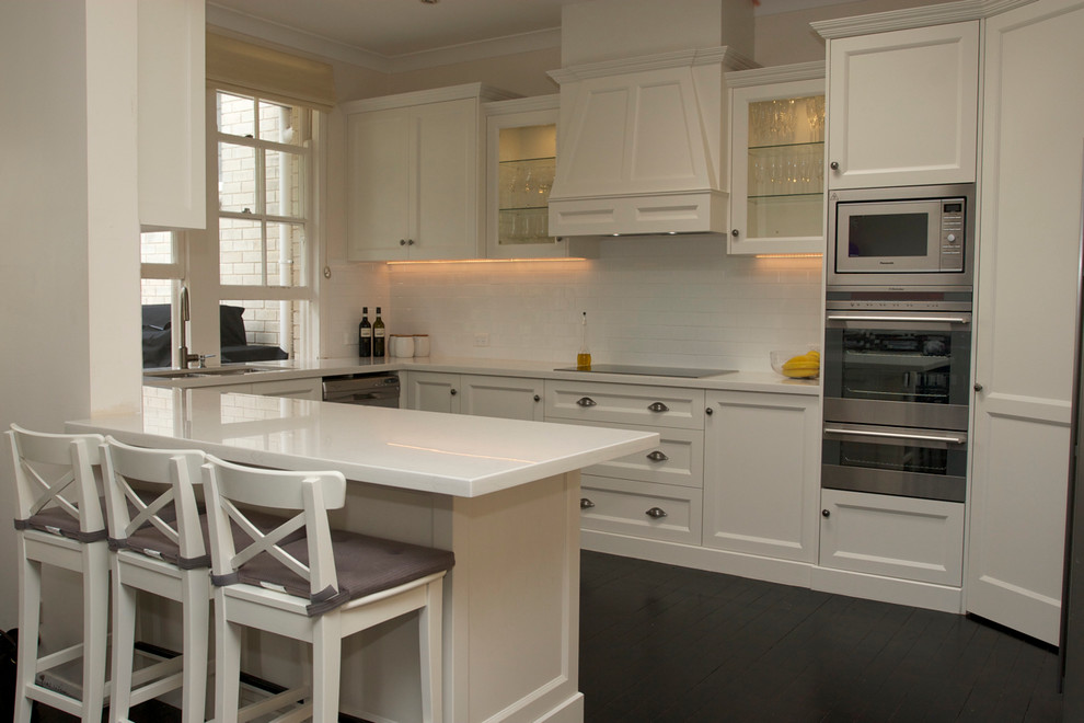Klassisk inredning av ett mellanstort kök, med en undermonterad diskho, luckor med infälld panel, vita skåp, bänkskiva i koppar, vitt stänkskydd, stänkskydd i keramik, rostfria vitvaror och målat trägolv