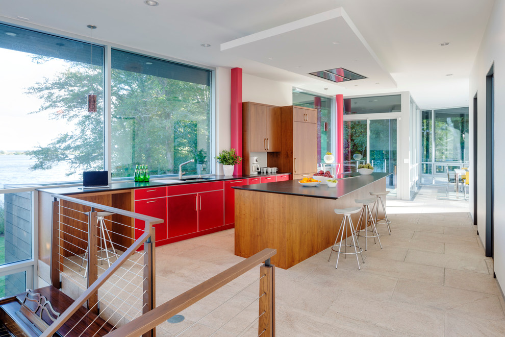 Ejemplo de cocina contemporánea con armarios con paneles lisos, puertas de armario rojas, electrodomésticos de acero inoxidable, una isla y fregadero bajoencimera