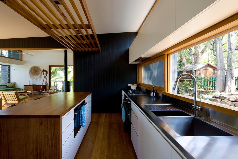 Exempel på ett modernt kök, med en dubbel diskho, vita skåp och bänkskiva i rostfritt stål