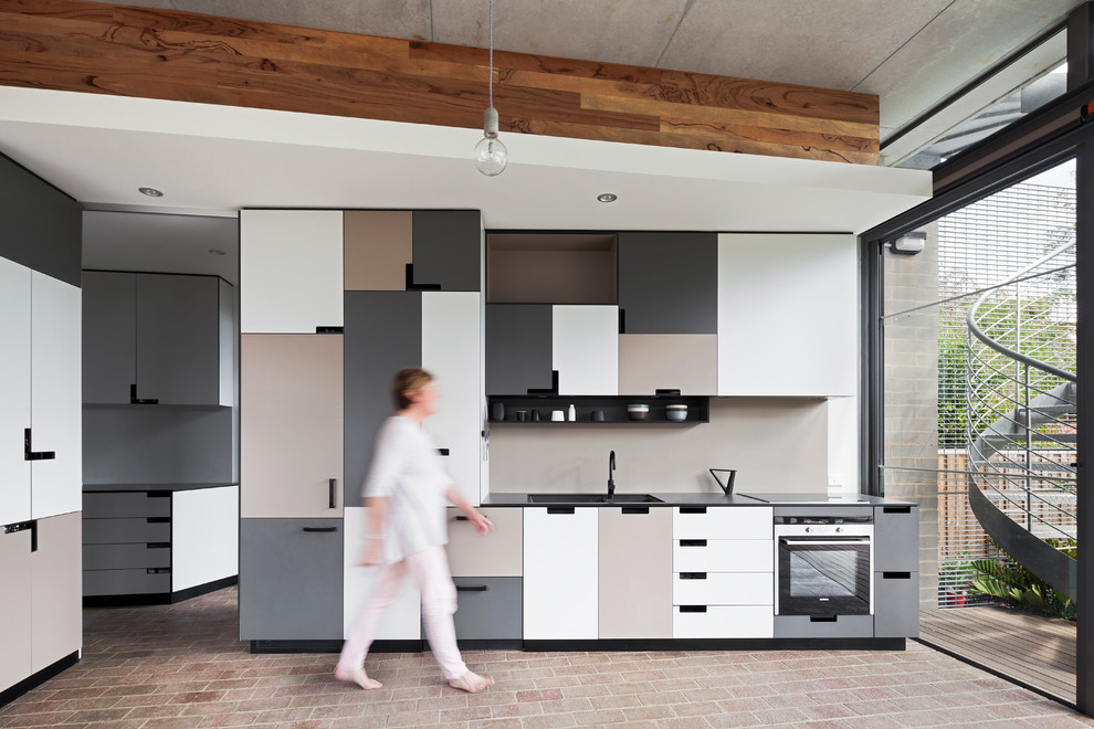 Zweizeilige Moderne Wohnküche ohne Insel mit Unterbauwaschbecken, Laminat-Arbeitsplatte, Backsteinboden, flächenbündigen Schrankfronten, grauen Schränken und Küchenrückwand in Beige in Perth