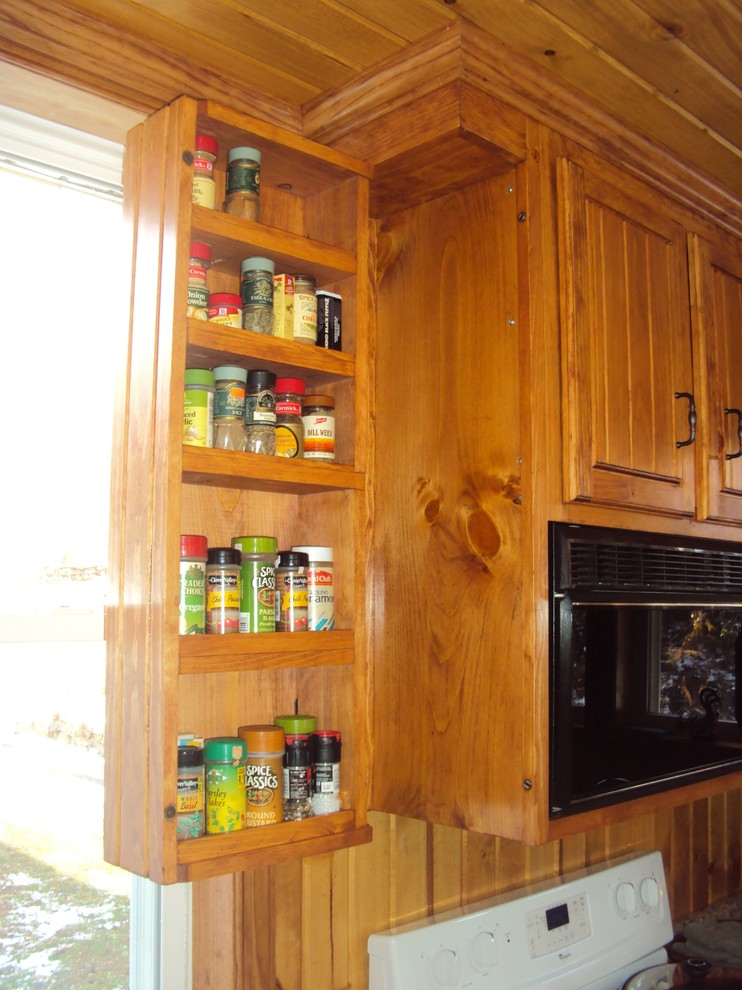Foto på ett mellanstort rustikt kök, med en dubbel diskho, luckor med upphöjd panel, skåp i mellenmörkt trä, bänkskiva i kvarts, svarta vitvaror och vinylgolv