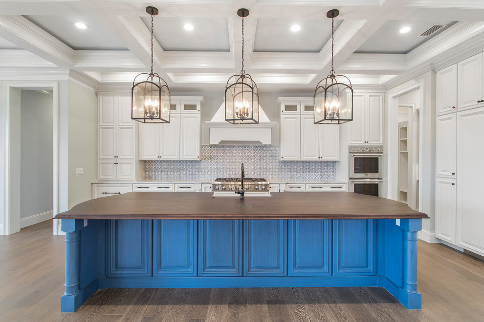 Large transitional galley light wood floor and brown floor eat-in kitchen photo in Jacksonville with a farmhouse sink, raised-panel cabinets, blue cabinets, wood countertops, blue backsplash, ceramic backsplash, stainless steel appliances, an island and brown countertops