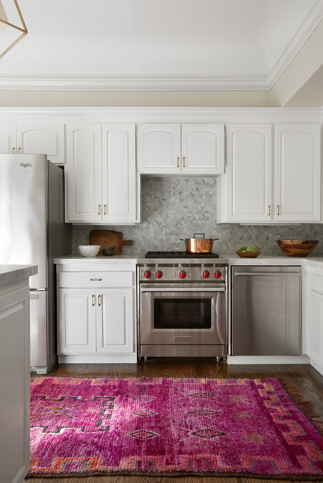 Inspiration for a transitional l-shaped dark wood floor kitchen remodel in San Francisco with a farmhouse sink, raised-panel cabinets, white cabinets, gray backsplash, mosaic tile backsplash, stainless steel appliances and an island