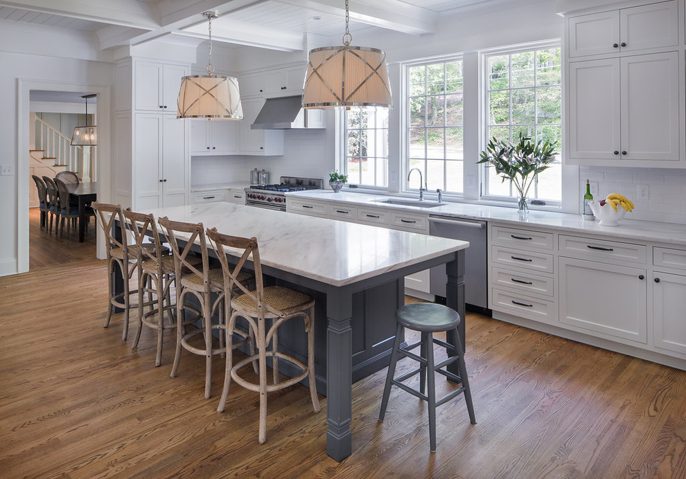 Inspiration for a mid-sized transitional l-shaped medium tone wood floor and brown floor kitchen remodel in Atlanta with an undermount sink, shaker cabinets, white cabinets, white backsplash, stainless steel appliances, marble countertops, ceramic backsplash and an island