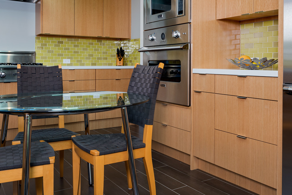 На фото: п-образная кухня в современном стиле с обеденным столом, плоскими фасадами, темными деревянными фасадами, серым фартуком, фартуком из керамической плитки и техникой из нержавеющей стали