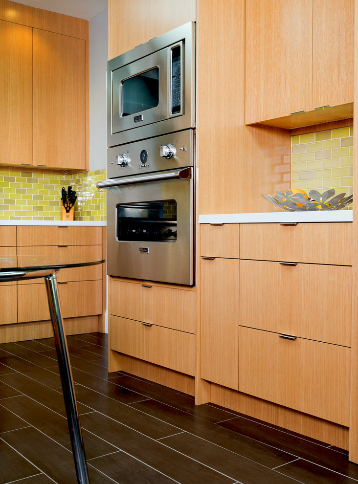 Cette photo montre une cuisine tendance en U et bois brun fermée avec un évier encastré, un placard à porte plane, une crédence verte, une crédence en céramique et un électroménager en acier inoxydable.