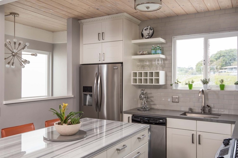 Modern inredning av ett mellanstort grå grått kök, med en enkel diskho, skåp i shakerstil, vita skåp, marmorbänkskiva, grått stänkskydd, stänkskydd i keramik, rostfria vitvaror, mörkt trägolv, en köksö och brunt golv
