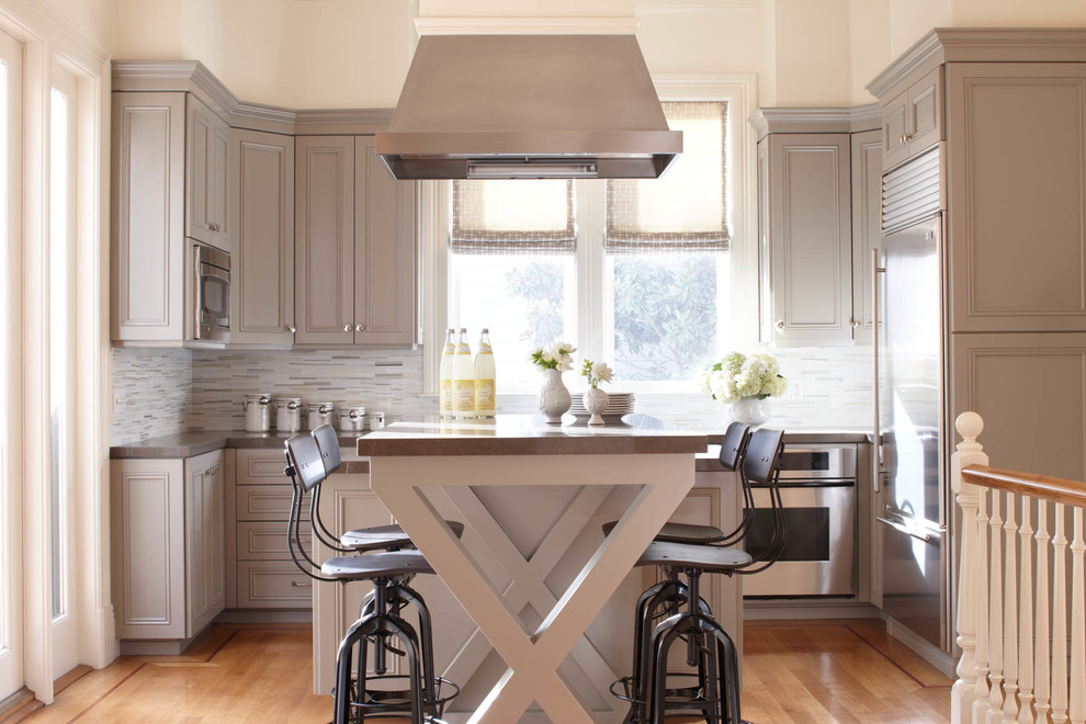 Bild på ett vintage u-kök, med luckor med infälld panel, grå skåp, flerfärgad stänkskydd, stänkskydd i mosaik, rostfria vitvaror, mellanmörkt trägolv och en köksö