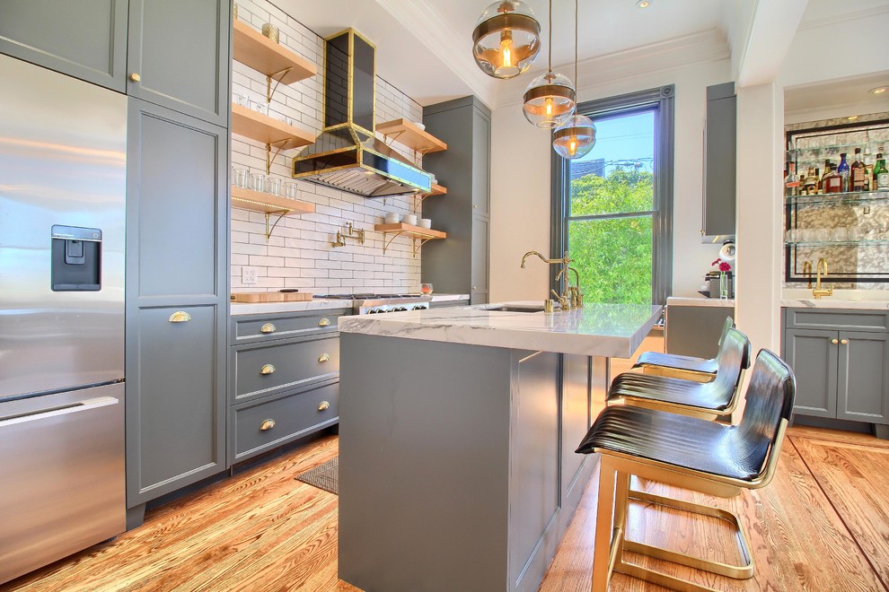 Exempel på ett mellanstort klassiskt linjärt kök med öppen planlösning, med en enkel diskho, skåp i shakerstil, grå skåp, marmorbänkskiva, gult stänkskydd, stänkskydd i tunnelbanekakel, svarta vitvaror, ljust trägolv, en köksö och brunt golv