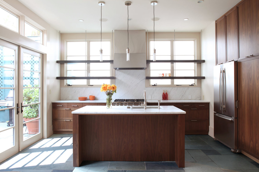Foto di una cucina a L moderna con ante con riquadro incassato, ante in legno bruno, paraspruzzi bianco e elettrodomestici in acciaio inossidabile