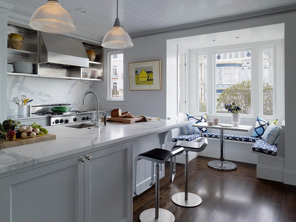 Large transitional galley dark wood floor eat-in kitchen photo in San Francisco with white backsplash, a double-bowl sink, shaker cabinets, white cabinets, marble countertops, stainless steel appliances, an island and marble backsplash