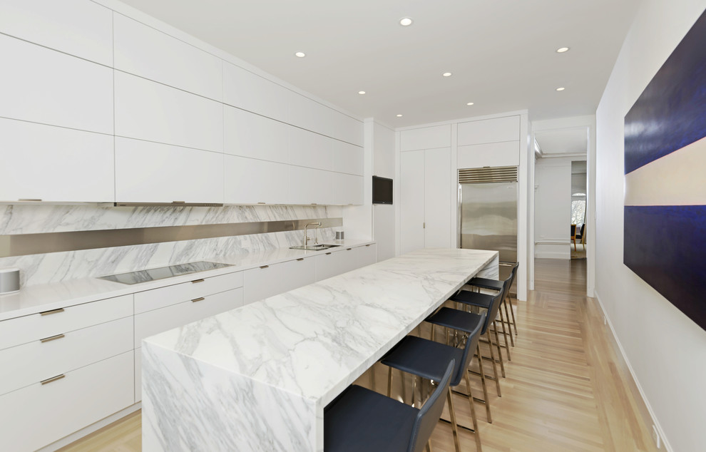 Inspiration for a large modern single-wall light wood floor eat-in kitchen remodel in San Francisco with a single-bowl sink, flat-panel cabinets, white cabinets, solid surface countertops, white backsplash, stone slab backsplash, stainless steel appliances and an island