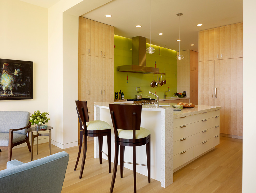 Стильный дизайн: кухня в современном стиле с плоскими фасадами, светлыми деревянными фасадами, зеленым фартуком, фартуком из стеклянной плитки и техникой из нержавеющей стали - последний тренд