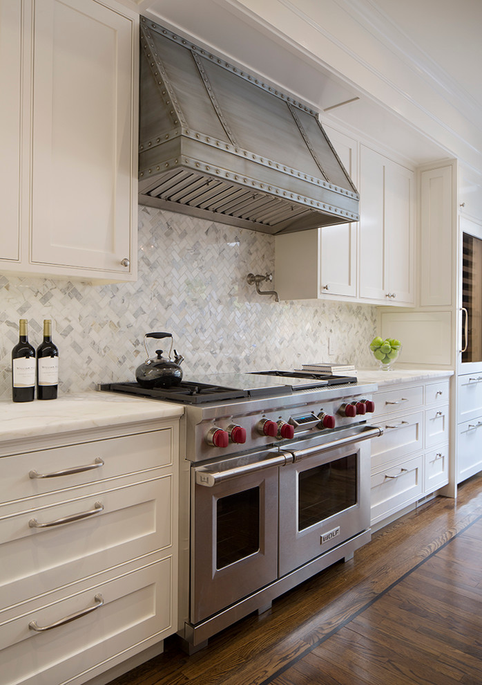Klassische Küche mit Kassettenfronten, weißen Schränken, Küchenrückwand in Weiß, Küchengeräten aus Edelstahl, dunklem Holzboden und Rückwand aus Marmor in San Francisco