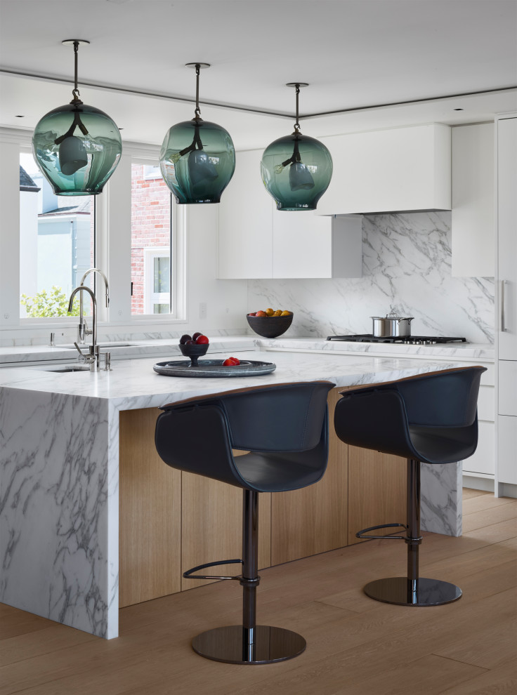 Inspiration for a huge modern u-shaped light wood floor and beige floor eat-in kitchen remodel in San Francisco with an integrated sink, flat-panel cabinets, white cabinets, marble countertops, white backsplash, marble backsplash, an island, white countertops and paneled appliances