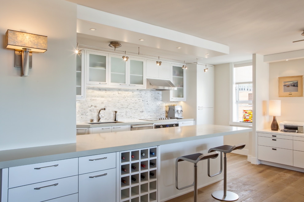 Photo of a contemporary kitchen in San Francisco with flat-panel cabinets, white cabinets, white splashback and stainless steel appliances.