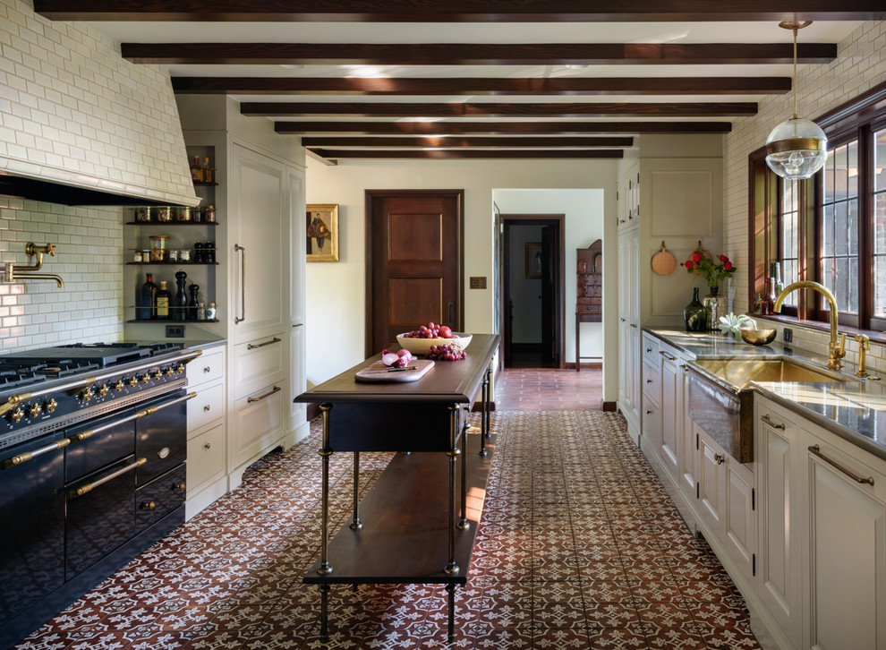 Inspiration for a timeless galley cement tile floor and brown floor kitchen remodel in Portland with a farmhouse sink, raised-panel cabinets, white cabinets, white backsplash, subway tile backsplash, black appliances, an island and gray countertops