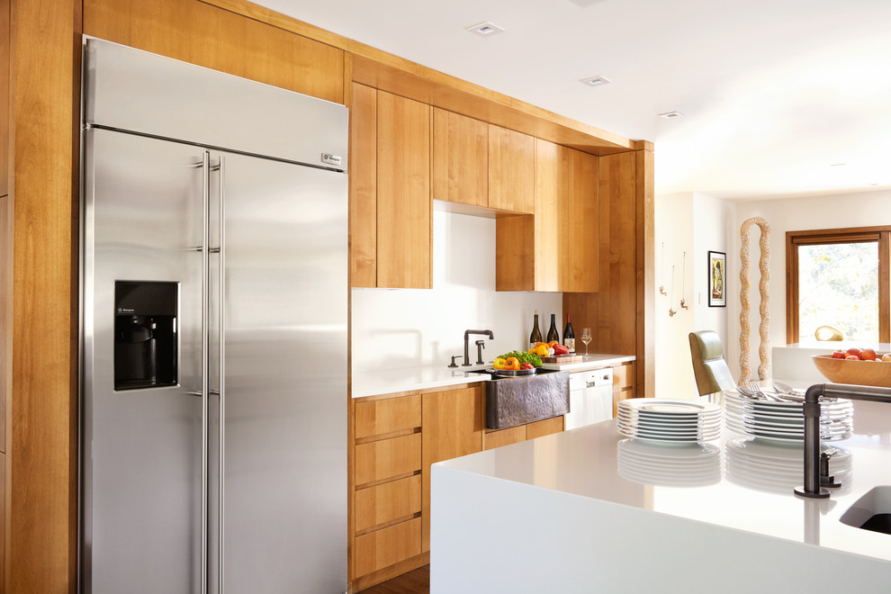 Modern inredning av ett stort vit vitt kök, med en rustik diskho, släta luckor, skåp i mellenmörkt trä, vitt stänkskydd, rostfria vitvaror, bänkskiva i kvartsit, mellanmörkt trägolv, en köksö och brunt golv