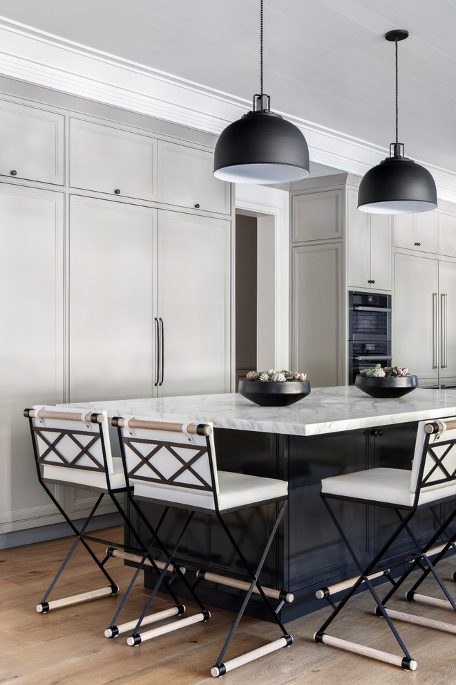 Foto på ett stort funkis vit kök, med skåp i shakerstil, grå skåp, marmorbänkskiva, vitt stänkskydd, ljust trägolv, flera köksöar och beiget golv