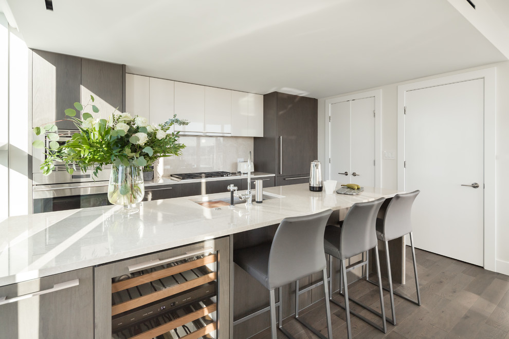 Small minimalist galley medium tone wood floor and gray floor eat-in kitchen photo in Vancouver with an undermount sink, flat-panel cabinets, dark wood cabinets, quartz countertops, beige backsplash, stainless steel appliances, an island and beige countertops