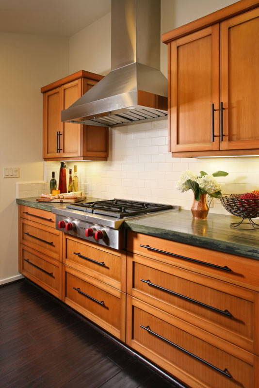 Mid-sized elegant galley dark wood floor eat-in kitchen photo in Los Angeles with an undermount sink, recessed-panel cabinets, medium tone wood cabinets, white backsplash, stainless steel appliances, granite countertops and subway tile backsplash