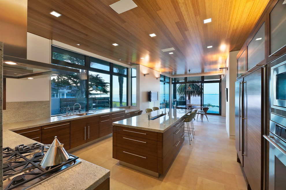 Aménagement d'une cuisine américaine encastrable moderne en U et bois brun avec un plan de travail en granite et un placard à porte plane.