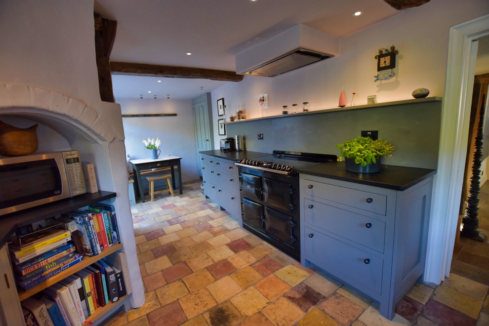 Inspiration for a large classic u-shaped kitchen/diner in Cambridgeshire with a submerged sink, shaker cabinets, green cabinets, granite worktops, green splashback, glass sheet splashback, black appliances, terracotta flooring and black worktops.