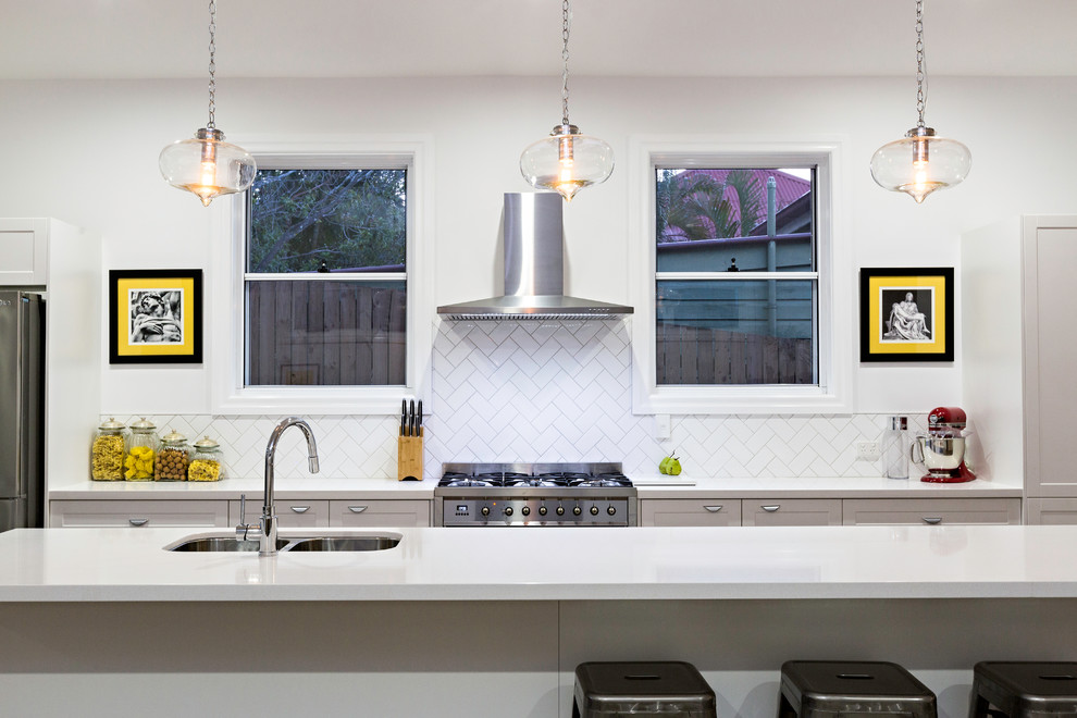 На фото: параллельная кухня в стиле неоклассика (современная классика) с двойной мойкой, фасадами в стиле шейкер, серыми фасадами, белым фартуком, техникой из нержавеющей стали и островом с
