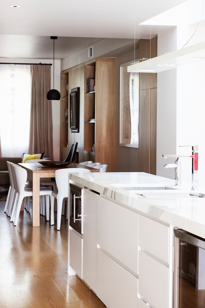 Zweizeilige, Mittelgroße Moderne Wohnküche mit Unterbauwaschbecken, flächenbündigen Schrankfronten, weißen Schränken, Marmor-Arbeitsplatte, Rückwand aus Spiegelfliesen, Küchengeräten aus Edelstahl, hellem Holzboden und Kücheninsel in Sydney