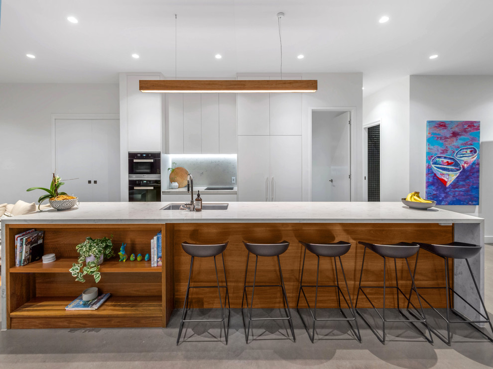 Imagen de cocina comedor minimalista de tamaño medio con fregadero bajoencimera, suelo de cemento, una isla, electrodomésticos de acero inoxidable y suelo gris