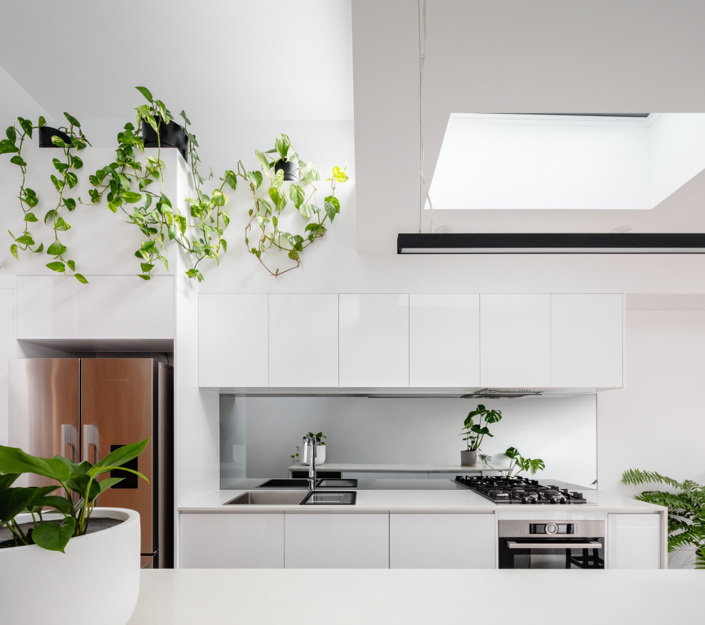 Foto de cocina abovedada contemporánea con armarios con paneles lisos, puertas de armario blancas, electrodomésticos de acero inoxidable, una isla y encimeras blancas