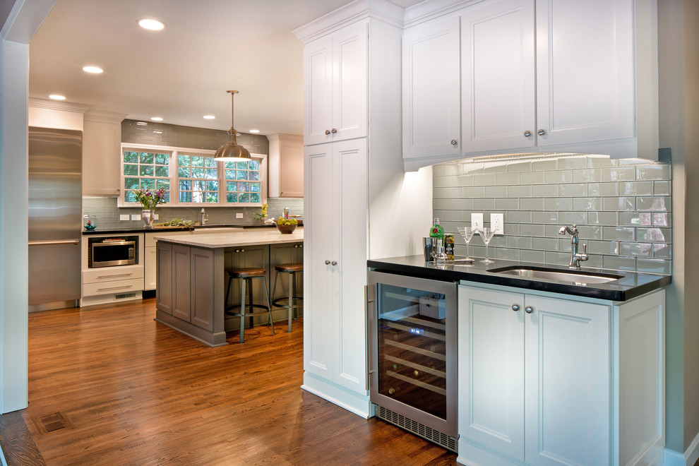 Exempel på ett mellanstort klassiskt kök, med en rustik diskho, luckor med infälld panel, vita skåp, marmorbänkskiva, grått stänkskydd, glaspanel som stänkskydd, rostfria vitvaror, mörkt trägolv, en köksö och brunt golv