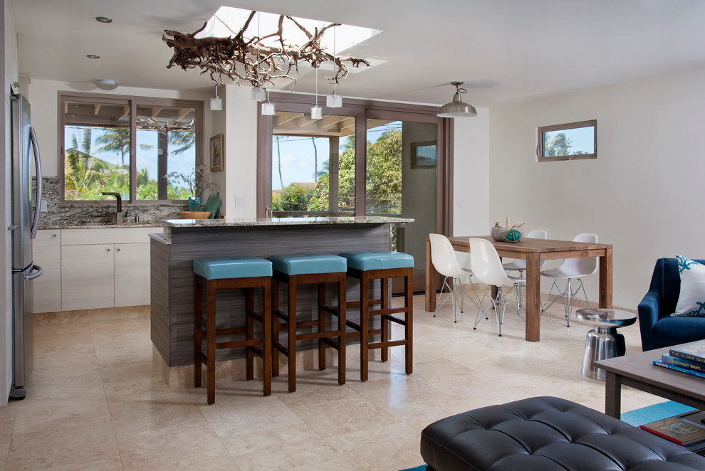 Photo of a beach style l-shaped open plan kitchen in Hawaii with flat-panel cabinets, white cabinets and stainless steel appliances.